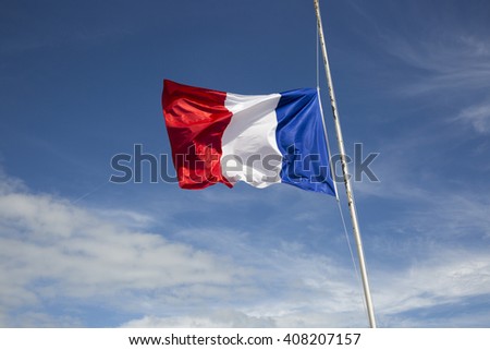 Flag of France floating in the wind in front of a blue sky background