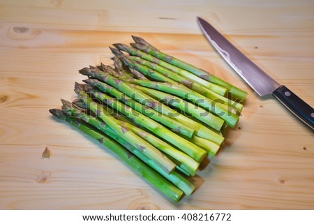 Bunch of green fresh asparagus or spargel in german on the chopping plate with kitchen knife just before cooking. Detailed Picture asparagus spears and heads just after harvest, delicious spring food.