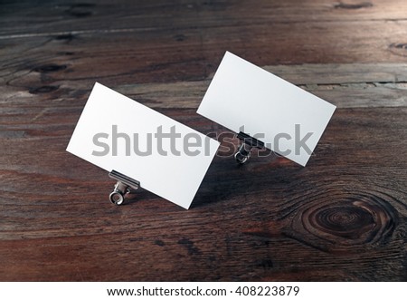 Blank business cards in paper clips on dark wooden background. Blank template for branding identity. Mock-up for design presentations and portfolios.