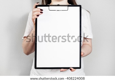 Woman holding clipboard with a blank sheet of paper. Blank paper poster in female hands. Blank template for graphic designers portfolios.