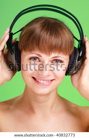 Smiling attractive woman with headphones on a green background