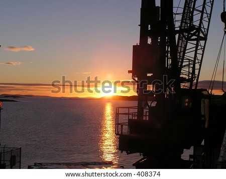 Sunrise from a boat with crane in foreground. Picture took near Tete-a-la-Baleine,"Whale Head" in St. Lawrence River, North Shore,Quebec, Canada.