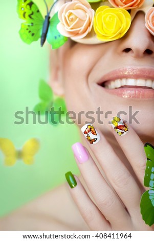 Multicolored manicure with pictures of butterflies on the nails and decorative rosettes on the eyes of a young woman.