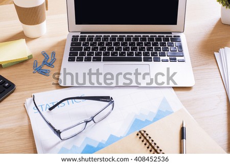 Topview of desktop with calculator, laptop keyboard, business report and office tools