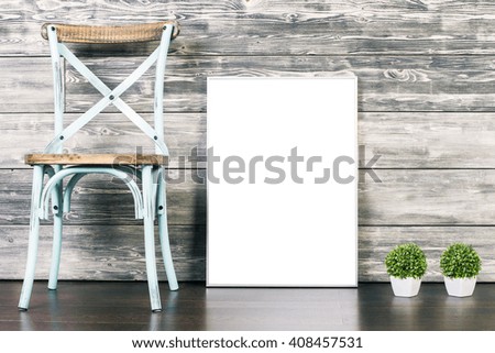 Blank picture frame, chair and two plants on wooden background. Mock up