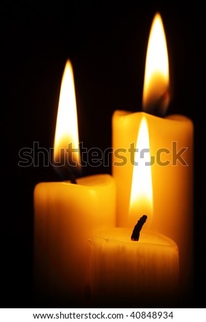 Three burning candles over a black background