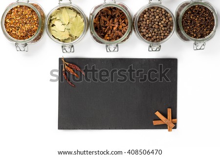 Spices and herbs in big glass jars. Food, cuisine ingredients. Wooden board with cinnamon, chilly. Kitchen photography.