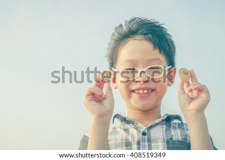 Young boy holding shell over sky background with vintage filter