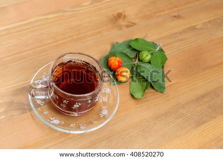 Fruit juice in cup and cherries on wood background.
