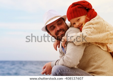 Father and little girl playing on the beach at the sunset