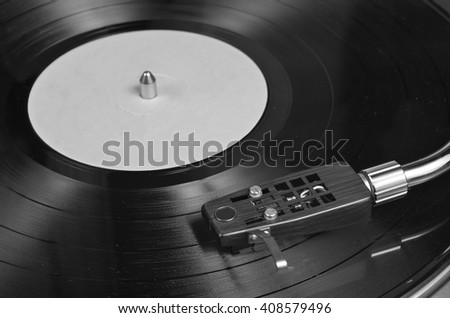 Vinyl record playing on a turntable in Monochrome. Music, dance and vintage theme Royalty-Free Stock Photo #408579496