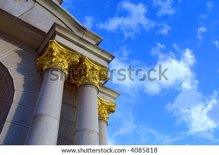 Greek-style columns with golden tops against sky. Shot in Kiev, Ukraine.