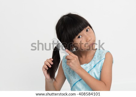 Asian girl brushing her hair on gray background.