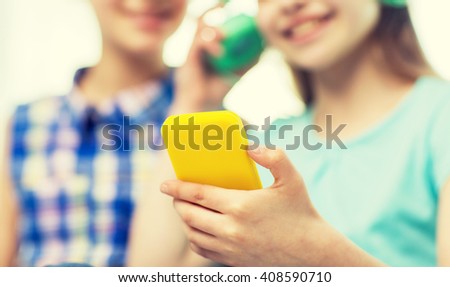 people, children, technology and friends concept - close up of happy little girls with smartphone and earphones listening to music