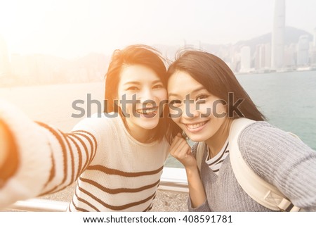 Asian young girls take a selfie with her friends at Victoria Harbor, Hong Kong.