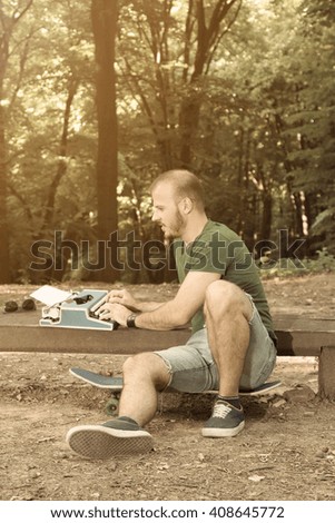 Young writer finding inspiration in the park while sitting on his skateboard 