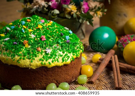 Easter celebrating family dinner, multicolored eggs, flowers, sweet sprinkled cakes, cupcakes, fruit herbal tea,  sweets on wooden table, food holiday photo