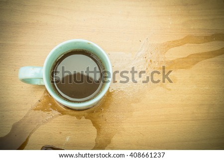 Cup of coffee spilled out on wooden desk (vintage style) Royalty-Free Stock Photo #408661237