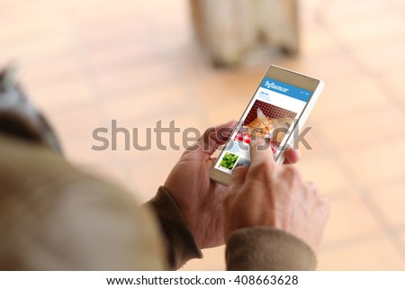 man touching the screen of his smartphone showing influencer social media profile. All screen graphics are made up.