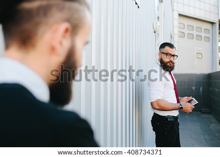 Two bearded businessman working on the street