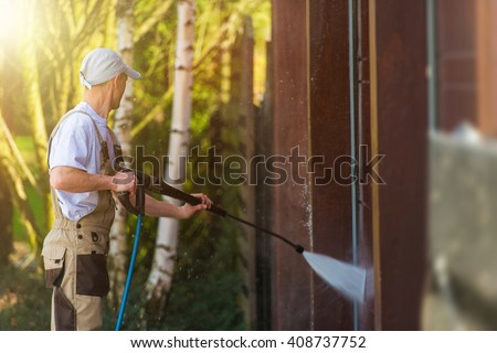 Garage Gate Water Cleaning. Garage Walls and Gate Powerful high Pressure Water Washing. Caucasian Worker Cleaning Building Elements. Royalty-Free Stock Photo #408737752