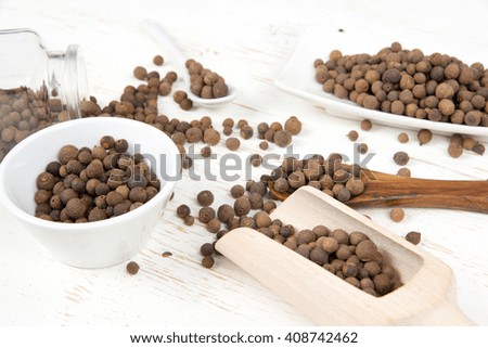 Photo of bowls full of allspice seeds on white wooden surface