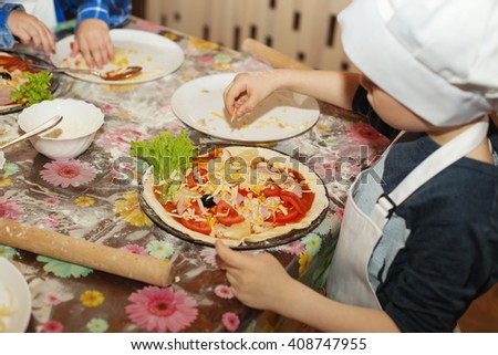 Children make pizza. Master class for children on cooking Italian pizza. Young children learn to cook a pizza. Kids preparing homemade pizza. Little cook.