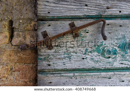 Old rusty latch on a wooden peeling door