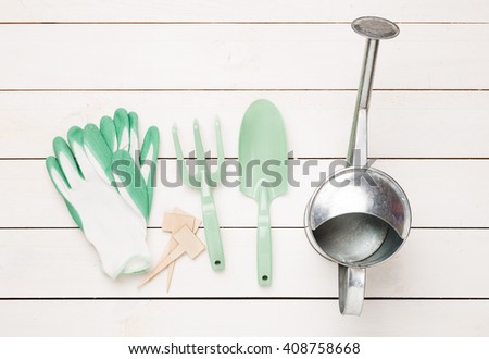 Gardening tools, watering can and gloves on white wooden table. Spring in the garden concept, top view, flat lay composition.