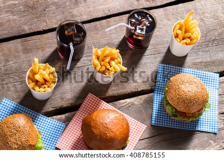 Hamburgers with fries and cola. Drinks and burgers on table. Energy for the whole day. Freshness and satiety.
