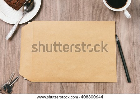 blank envelope on a table with a cup of espresso and a cupcake