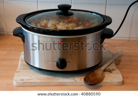 Slow cooker with wooden spoon on chopping board cheep winter cooking Royalty-Free Stock Photo #40880590