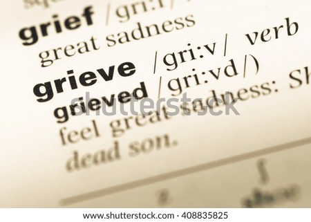 Close up of old English dictionary page with word grieve