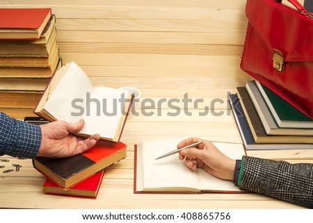 Closeup of business partners hand pointing where to sign a contract, legal papers or application form. Business meteeng.  On a wooden table books, documents, calculator, red briefcase. Copy space.