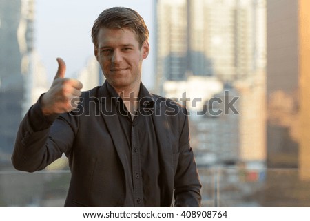 Businessman giving thumbs up outdoors