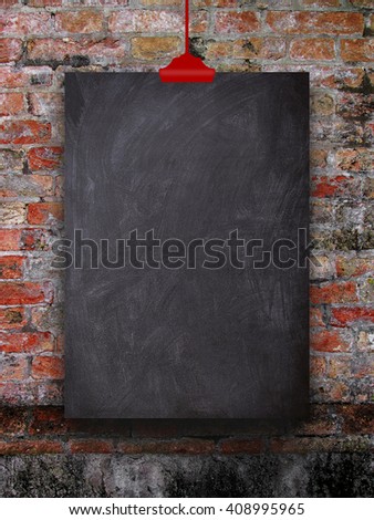 Close-up of one blank blackboard frame hanged by red clip against weathered brick wall background
