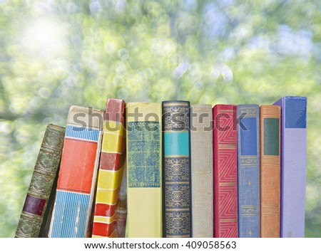 row of old books,against blurred tree background