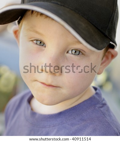 Color portrait of very cute four year old boy with blue eyes wearing a black baseball cap