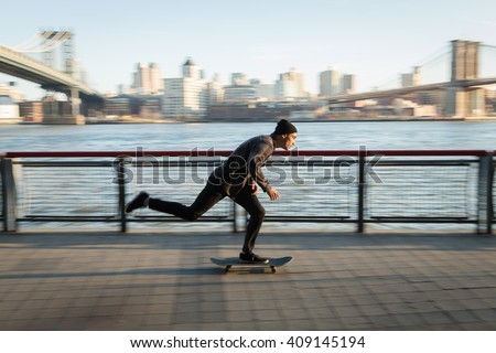 Young skateboarder in casual clothes cruise down on pedestrian walk in New York City.