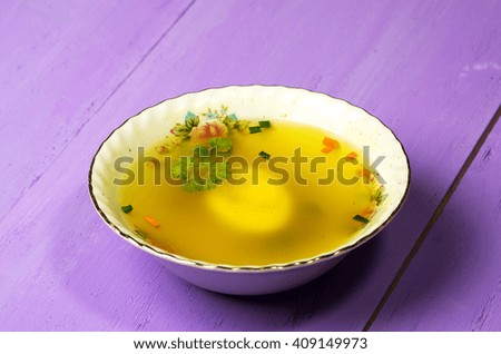 clear soup with vegetables in plate on wooden table .Rustic style.