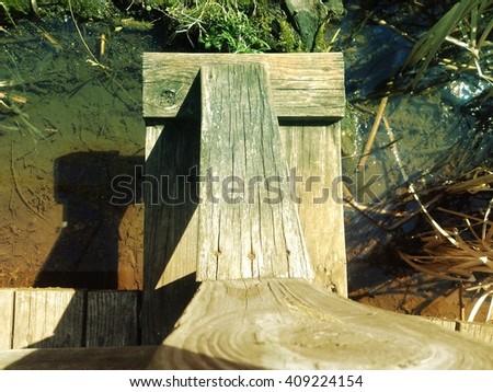 Wooden edge of bridge hoovers over the water