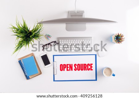 Office desk with OPEN SOURCE paperwork and other objects around, top view