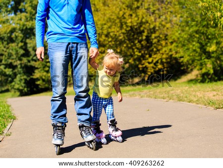 father teaching little daugther to roller skate in summer