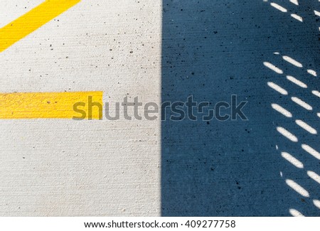 Abstract shadow on concrete floor. Yellow parking line on ground. Shadow on cement stone floor. Pavement with shadow and yellow line on ground. Abstract industrial design. Abstract minimal design.