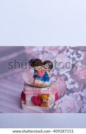 A lovely couple ceramic dolls in glass ball over sweet rose bouquet and blank space background