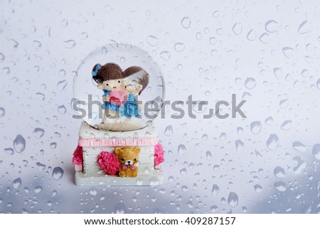A lovely couple ceramic dolls in glass ball over natural rain drops background