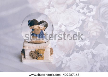 A lovely couple ceramic dolls in glass ball over sweet rose bouquet background