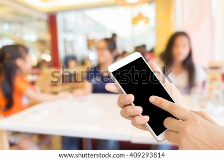 woman use mobile phone and blurred image of people in the restaurant