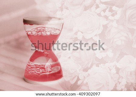 A lovely red liquid hourglass on the rose bouquet background, filtered color tone