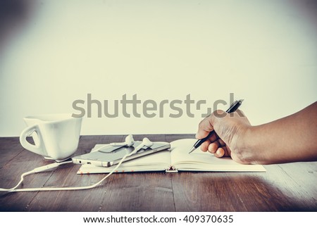 Notebook with pen, smart phone and coffee cup on wooden table